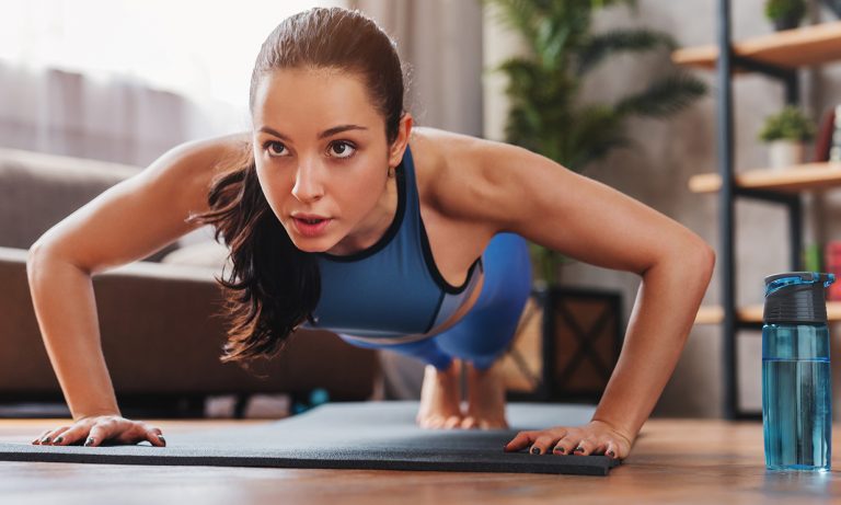 young woman performing pushups indoors 768
